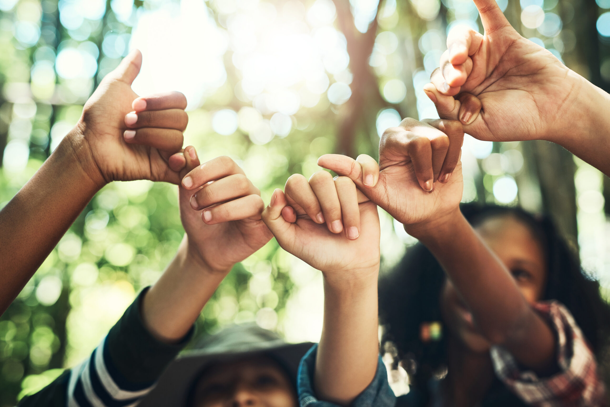 Friends forever to the camp and back. Shot of a group of teenagers linking fingers at summer camp